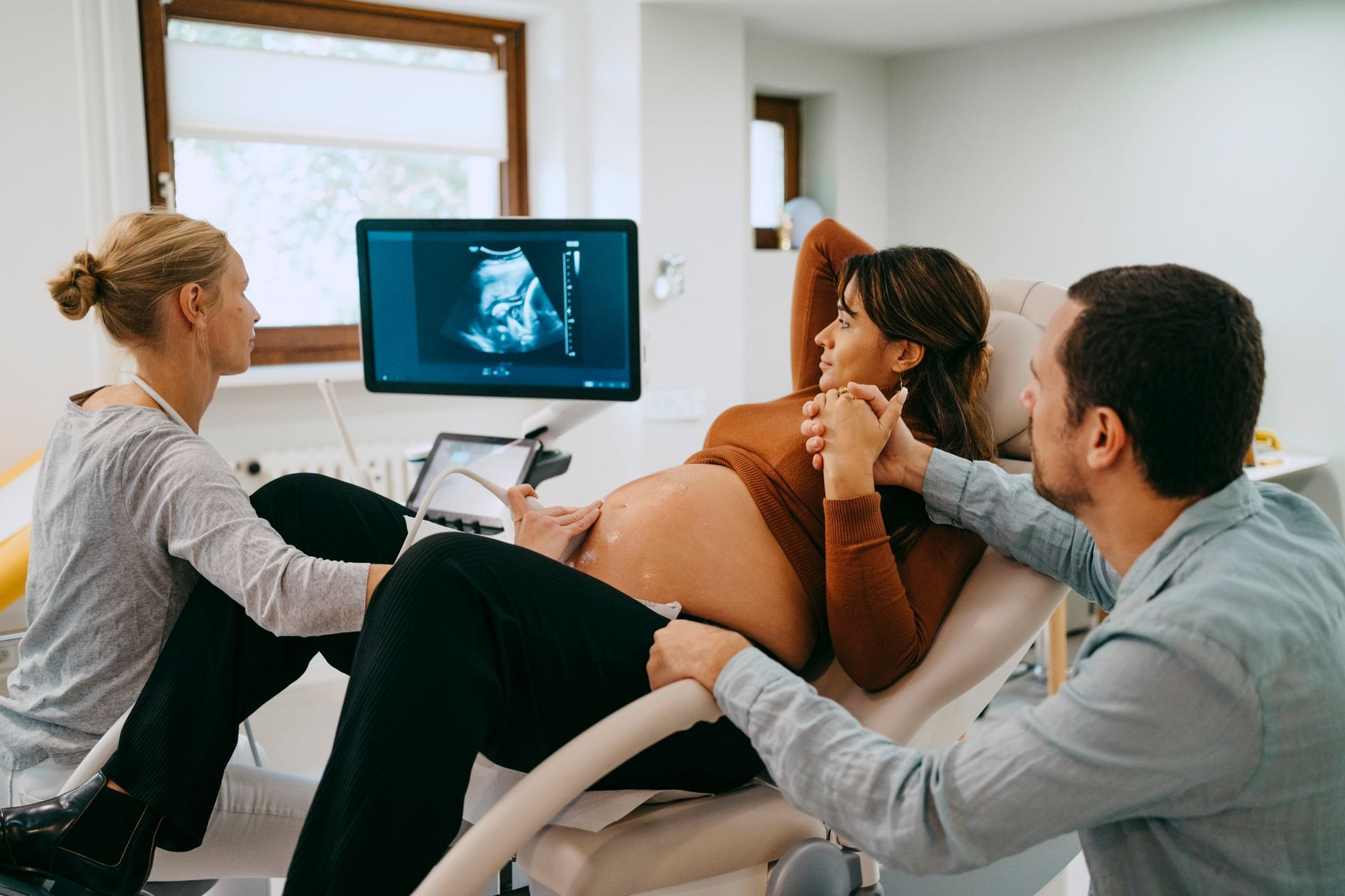 A pregnant woman is getting an ultrasound from a doctor.