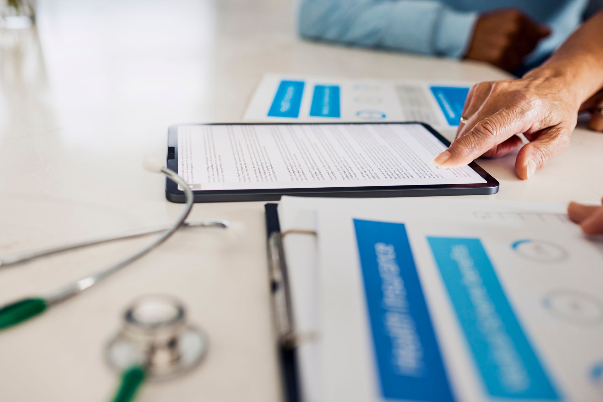 A person is sitting at a table looking at a tablet.