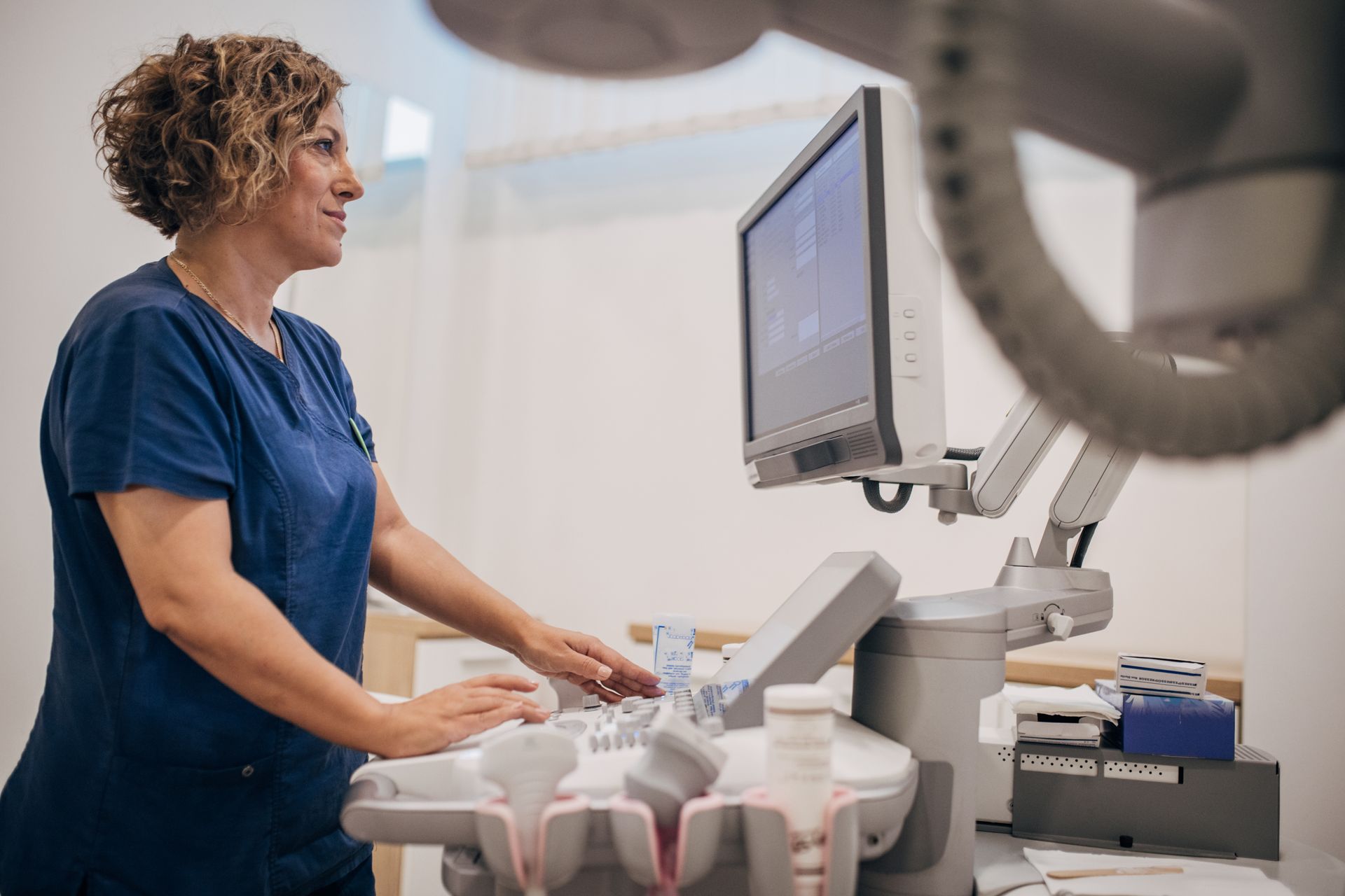 A female doctor is using an ultrasound machine in a hospital.