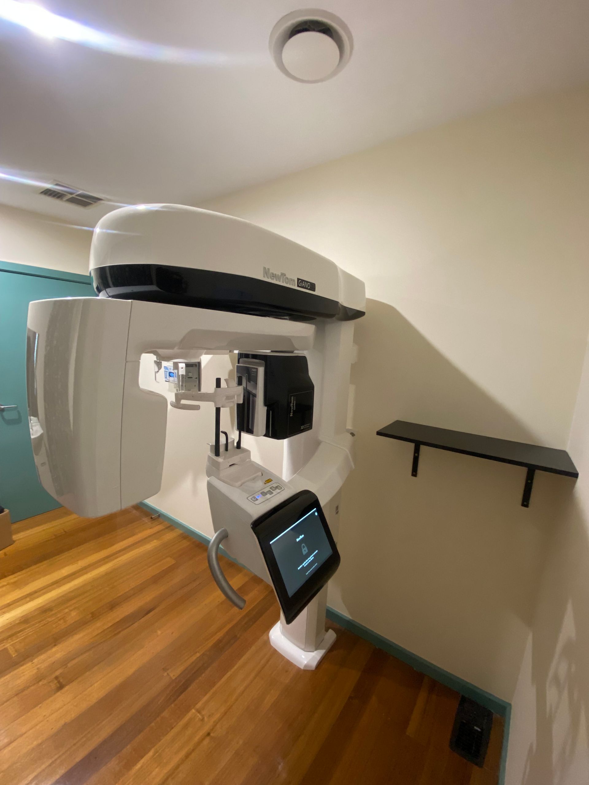 A woman is sitting in a dental chair looking at an x-ray of her teeth.