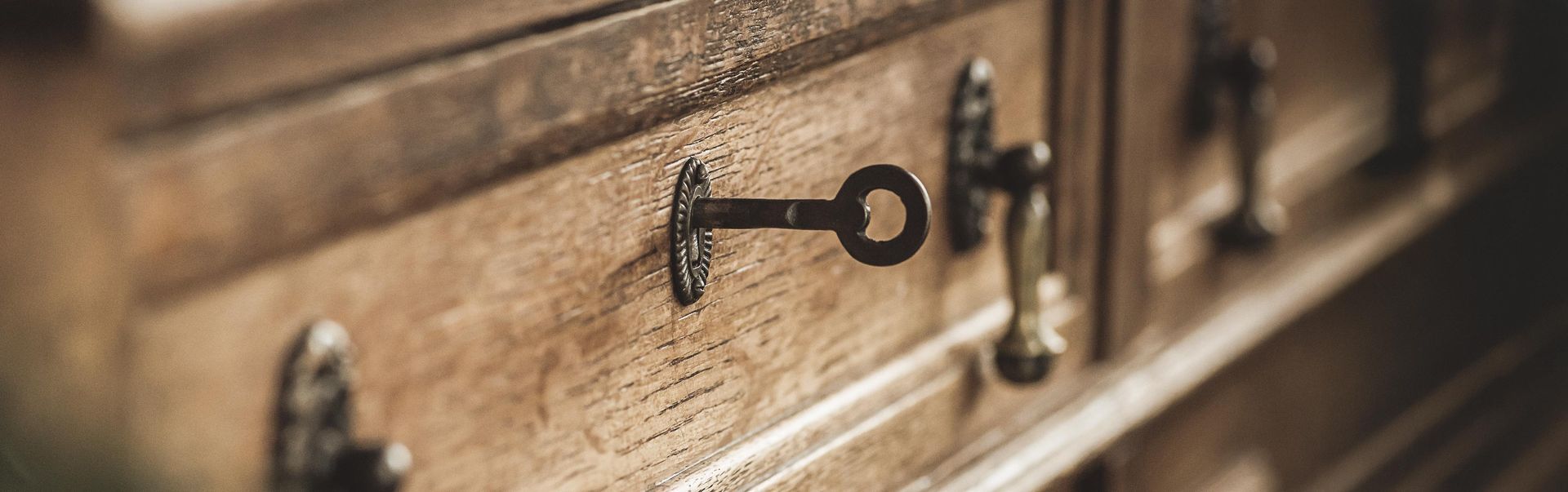Close-up of a wooden antique cabinet with a key in the lock.