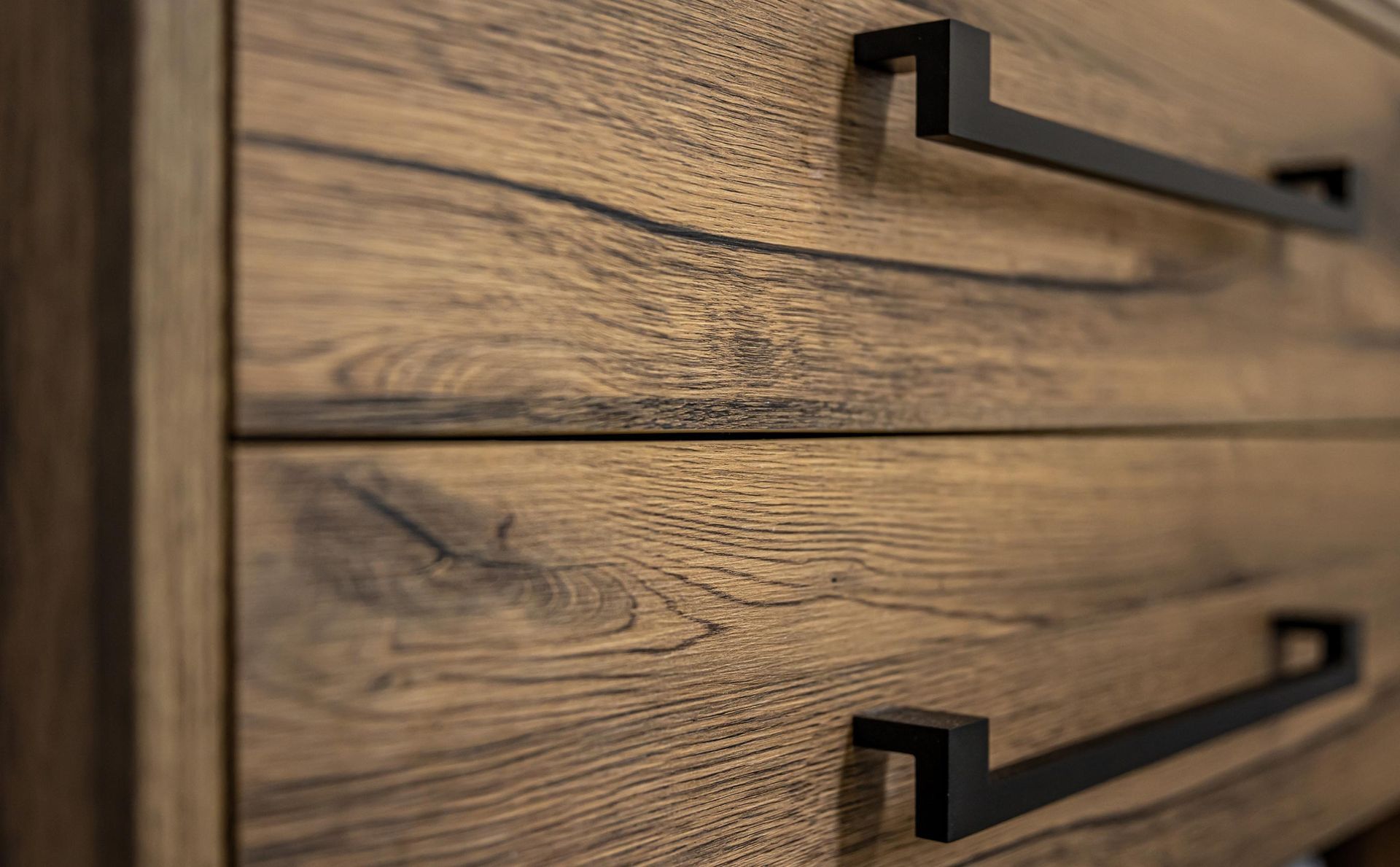 Wooden dresser with black metal drawer pulls. Close-up detail shows wood grain and hardware.