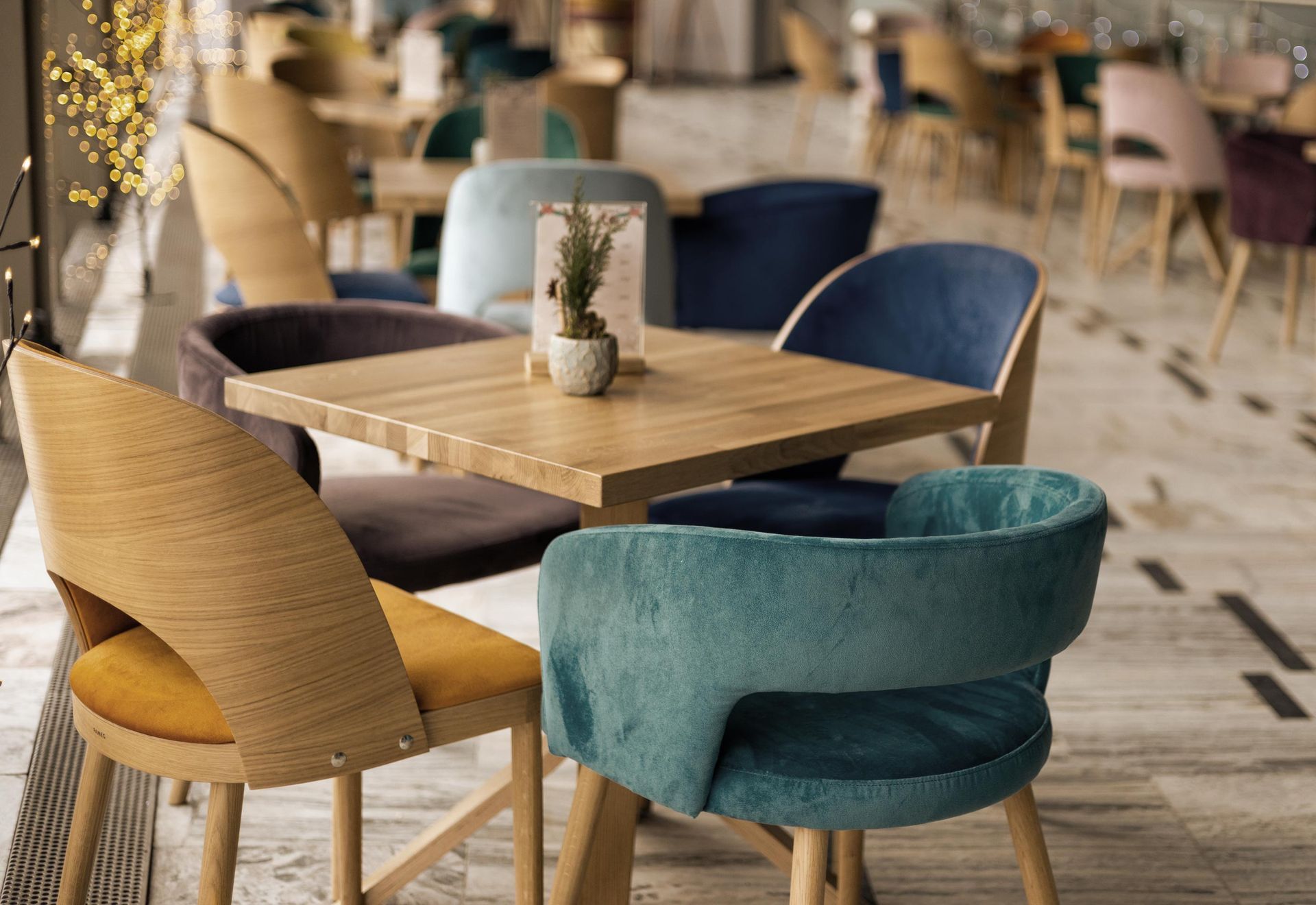 A restaurant table with four colorful upholstered chairs, set on a light wood floor.
