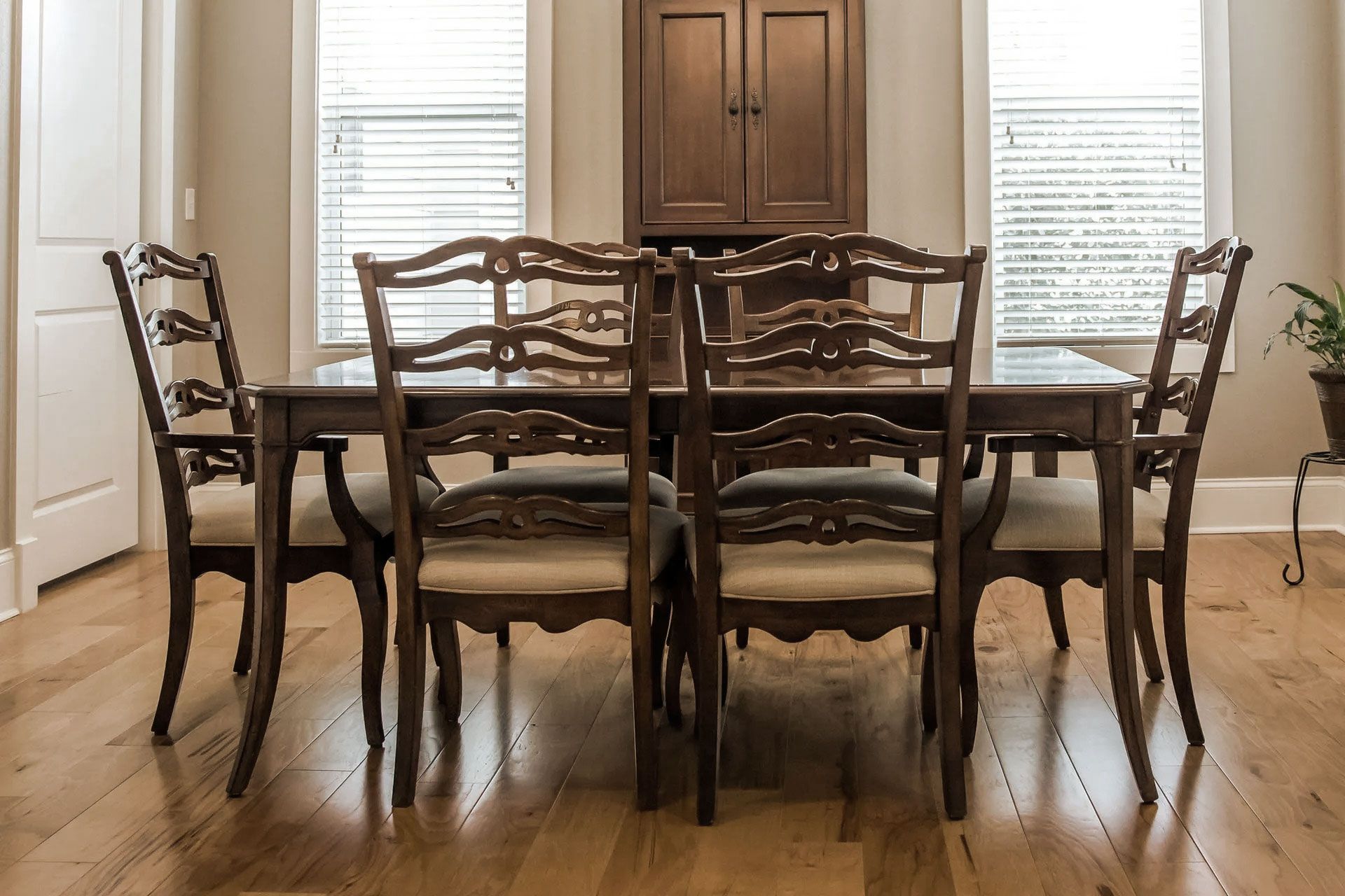 Dining room with a wooden table and six chairs, with a cabinet in the background.
