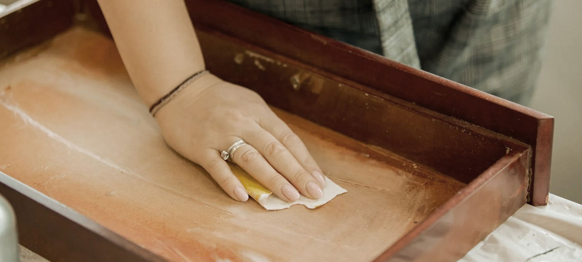 Person sanding the inside of a wooden drawer.