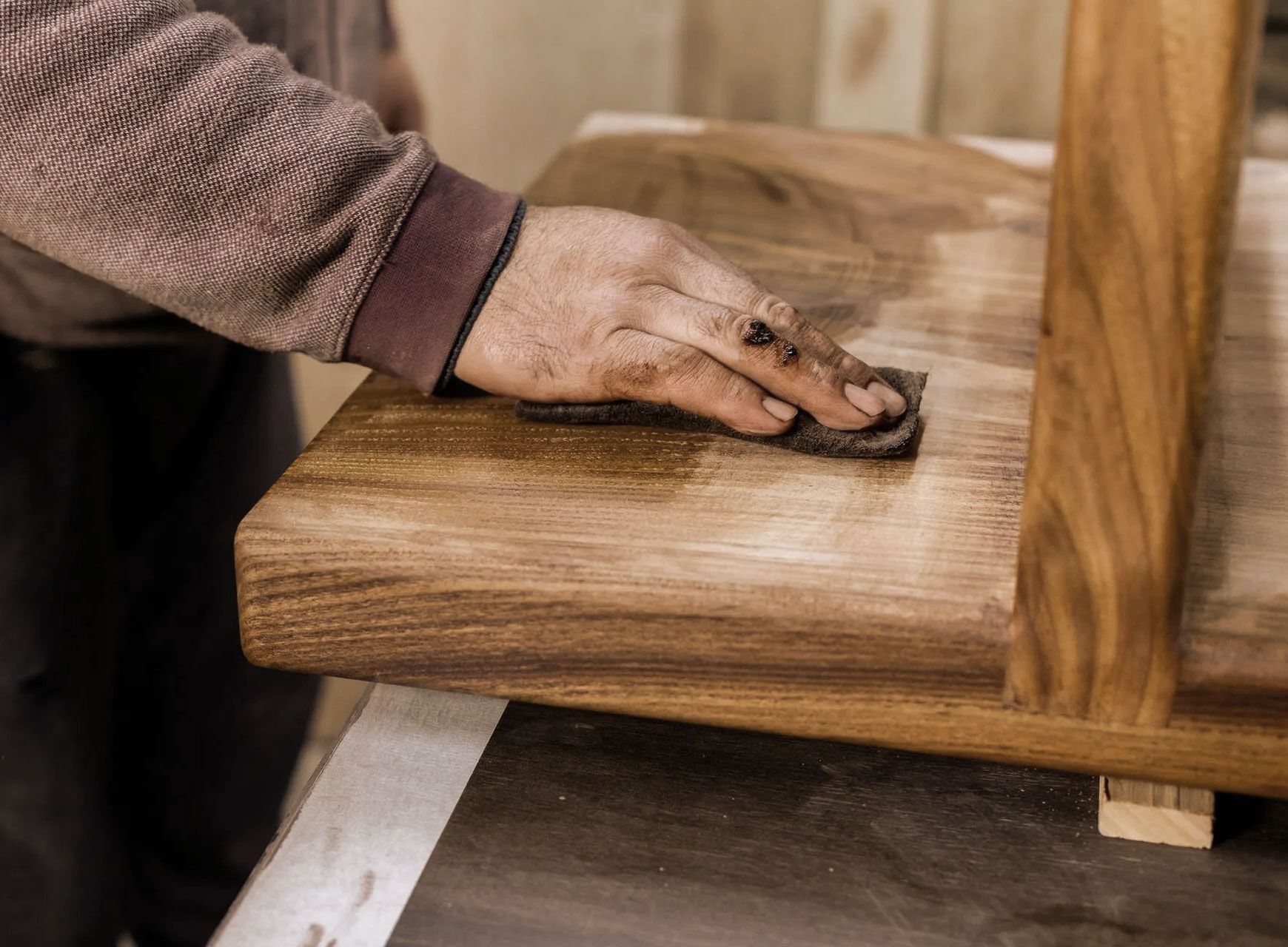 Hand sanding a wooden tabletop.