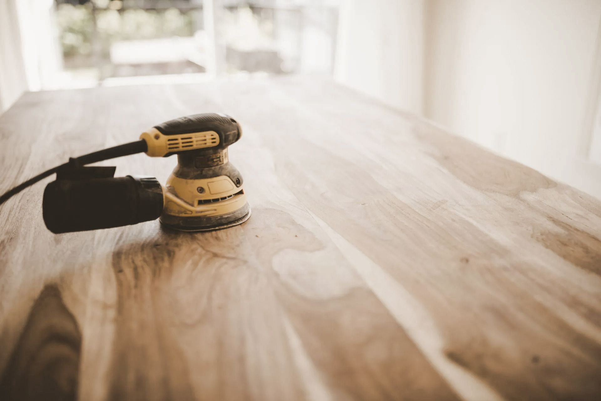 Electric sander on a wooden table, sanding the surface.