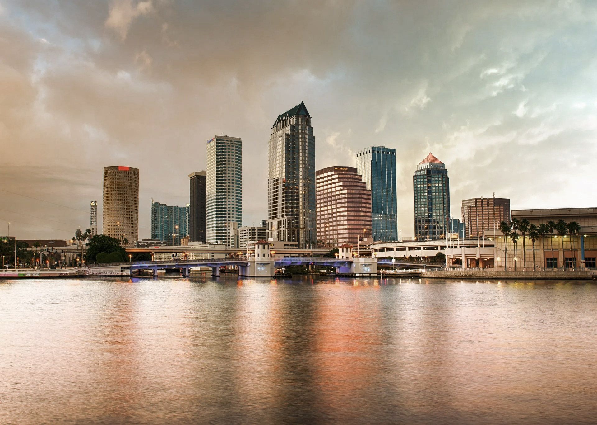 City skyline along a body of water under a cloudy sky.
