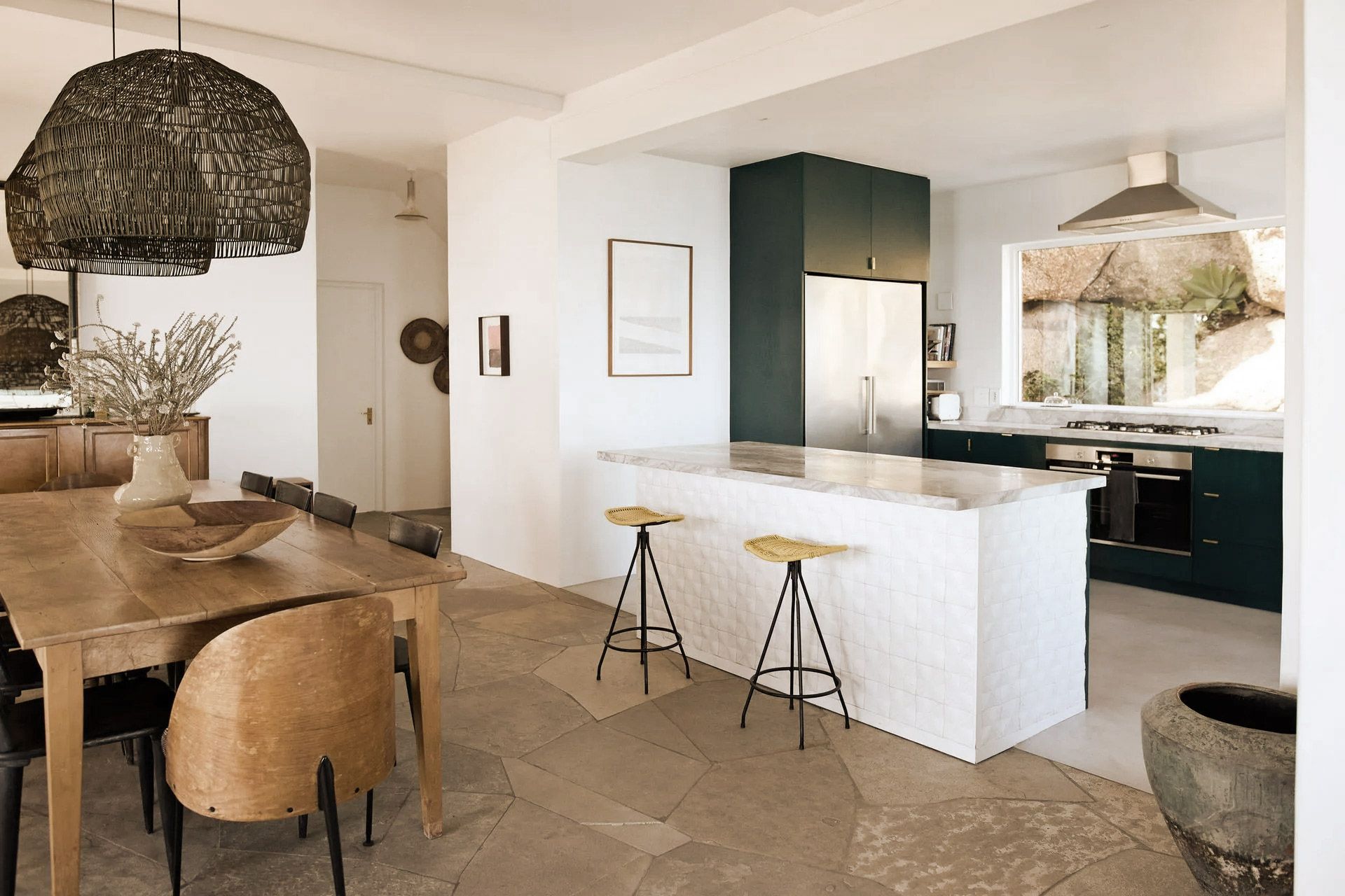 Kitchen with dining area. Green cabinets, white island, wood table, and natural light.
