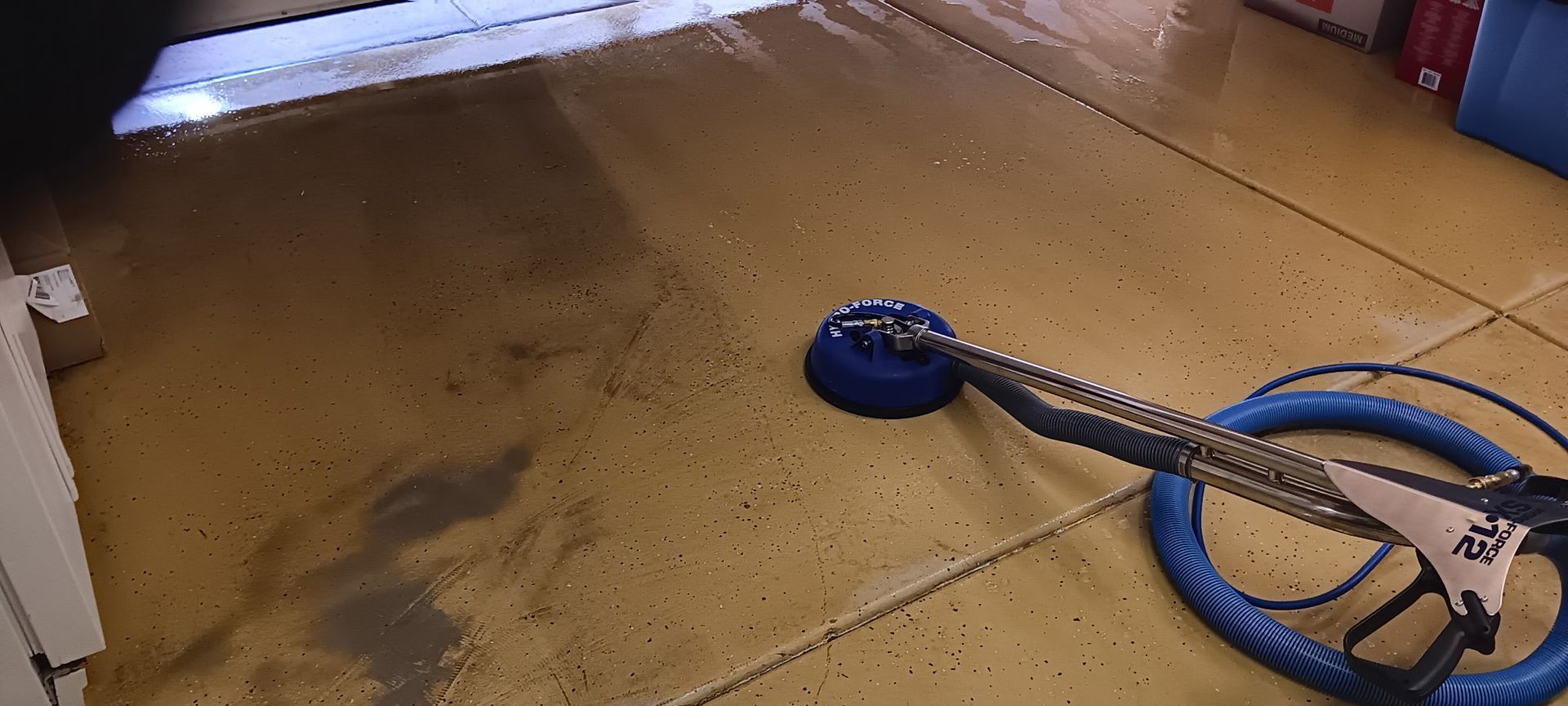 Person in blue overalls cleaning a white carpet with a yellow vacuum cleaner.