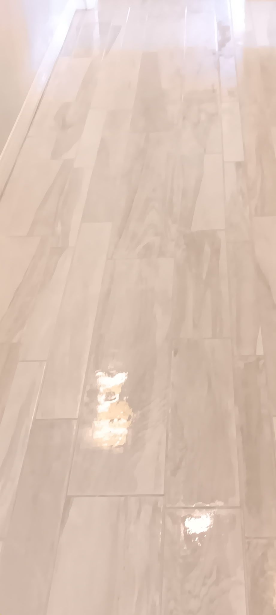 A person in grey work pants vacuums a grey carpet with a wet vacuum. A yellow vacuum cleaner is in the background.