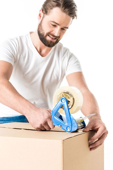Un hombre está pegando una caja de cartón con cinta adhesiva.