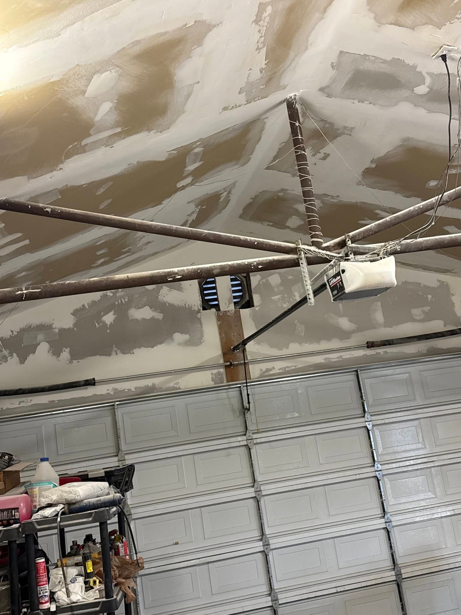 Garage interior with garage door, garage door opener, and ceiling with water damage.