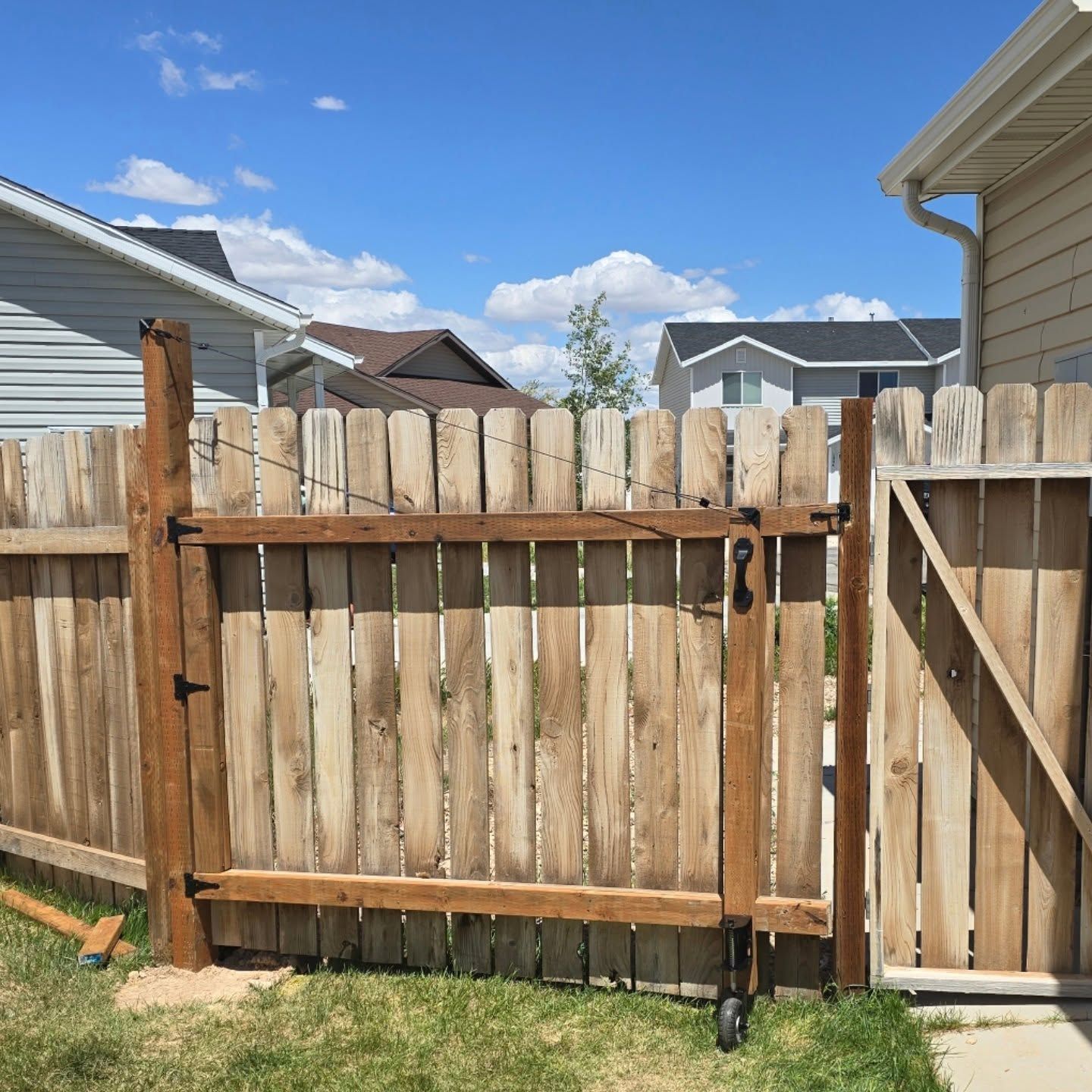 Wooden gate in a wooden fence, with blue sky background.