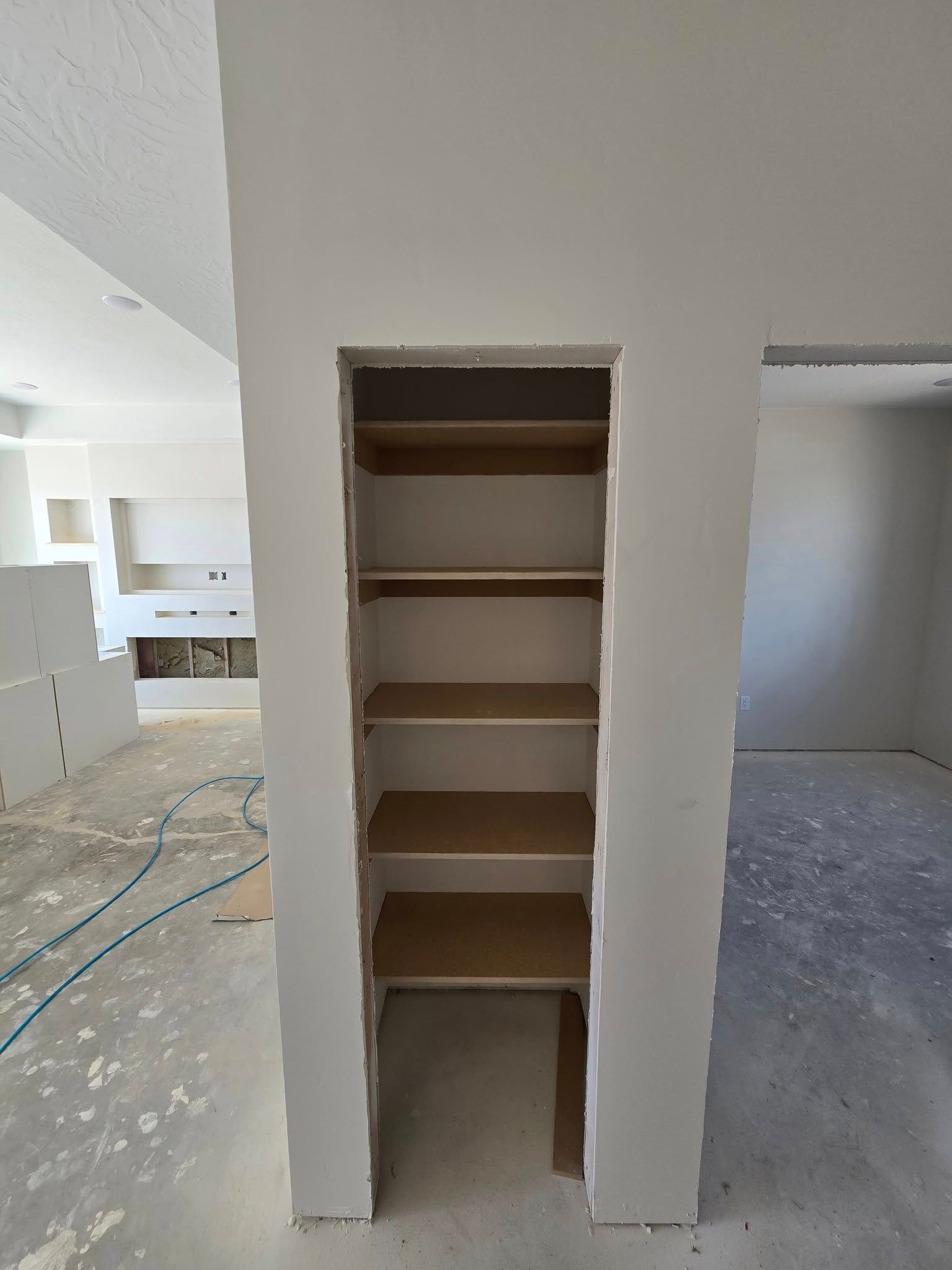 A built-in storage nook with several shelves in a room under construction.