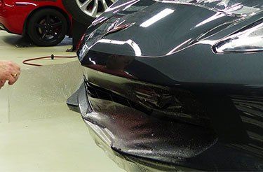 Gros plan d'une personne pulvérisant une voiture avec un vaporisateur.