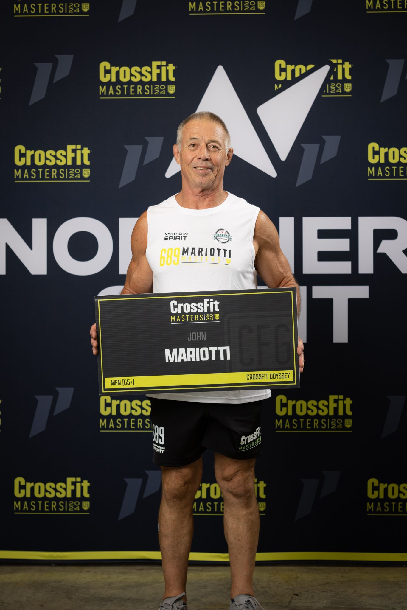 A man is holding a box in front of a crossfit banner.