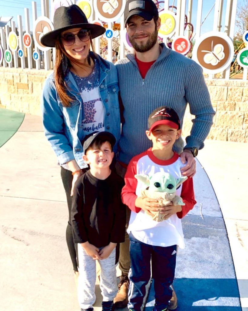 A family is posing for a picture in front of a playground.