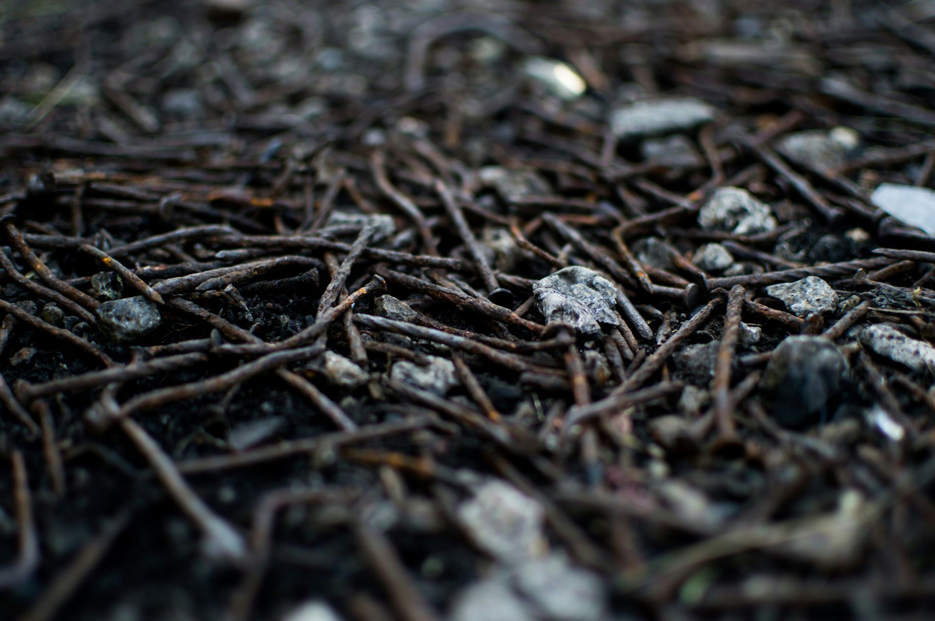 A pile of nails and rocks on the ground.