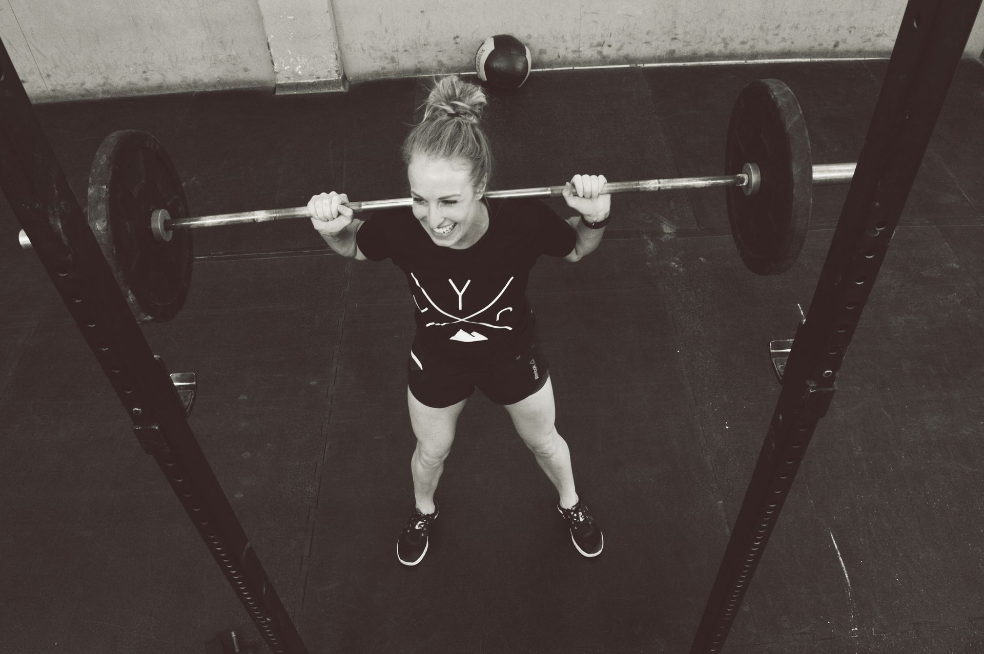 A woman is lifting a barbell over her head in a gym.