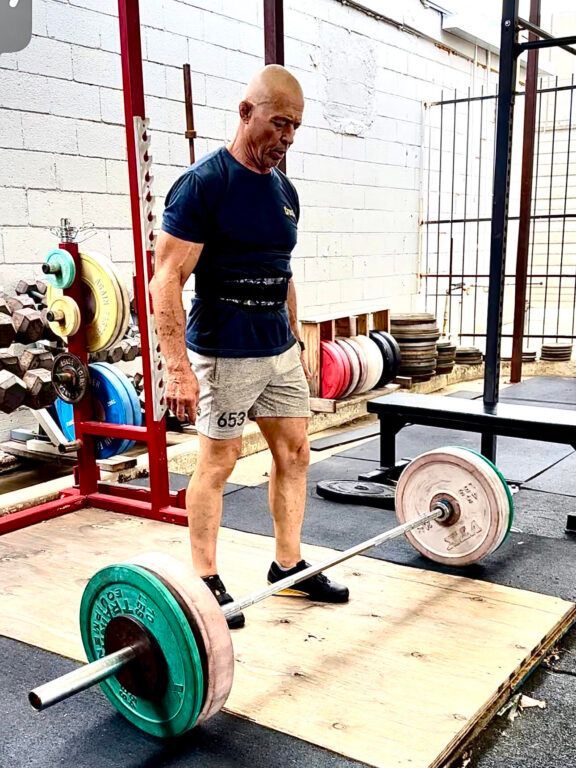 A man is lifting a barbell in a gym.