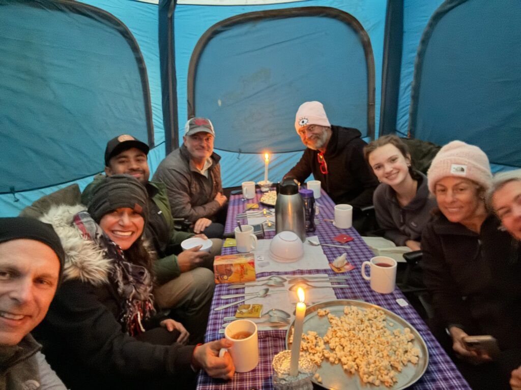 A group of people are sitting around a table in a tent.