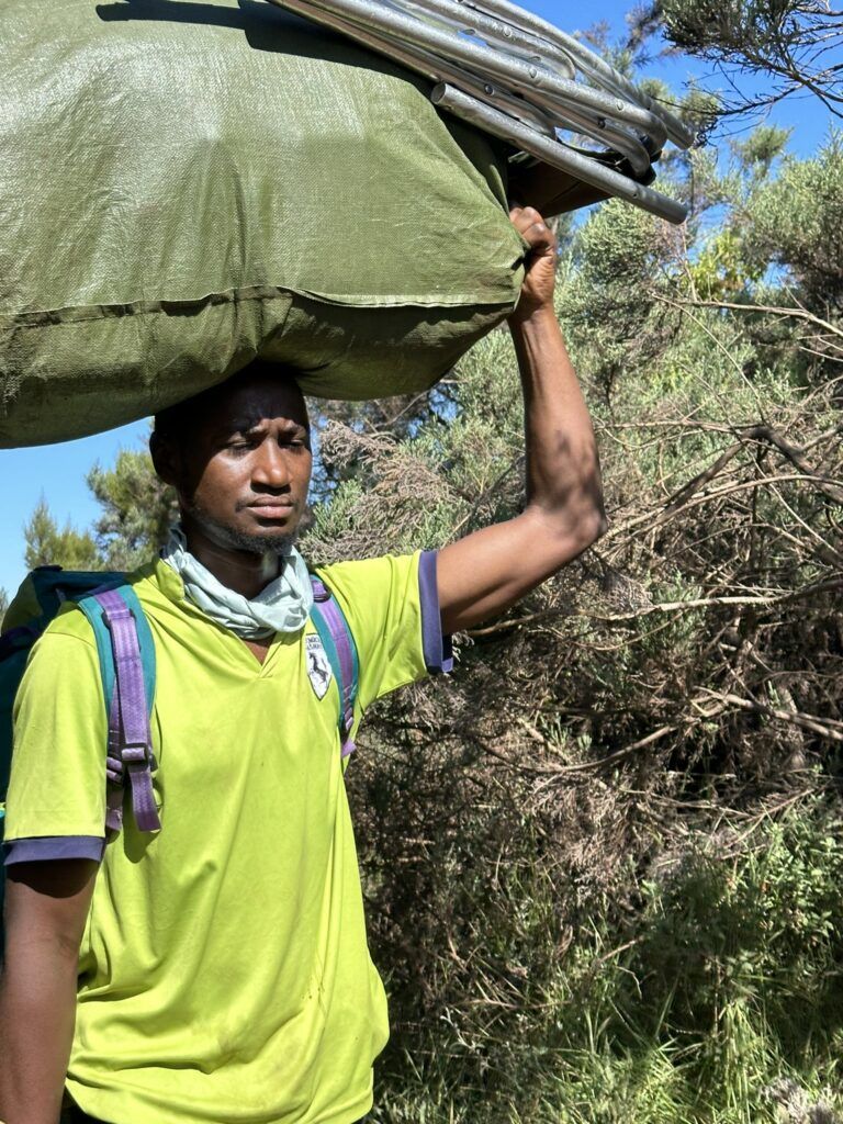 A man is carrying a large bag on his head.
