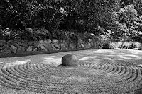 A black and white photo of a labyrinth with a rock in the middle.