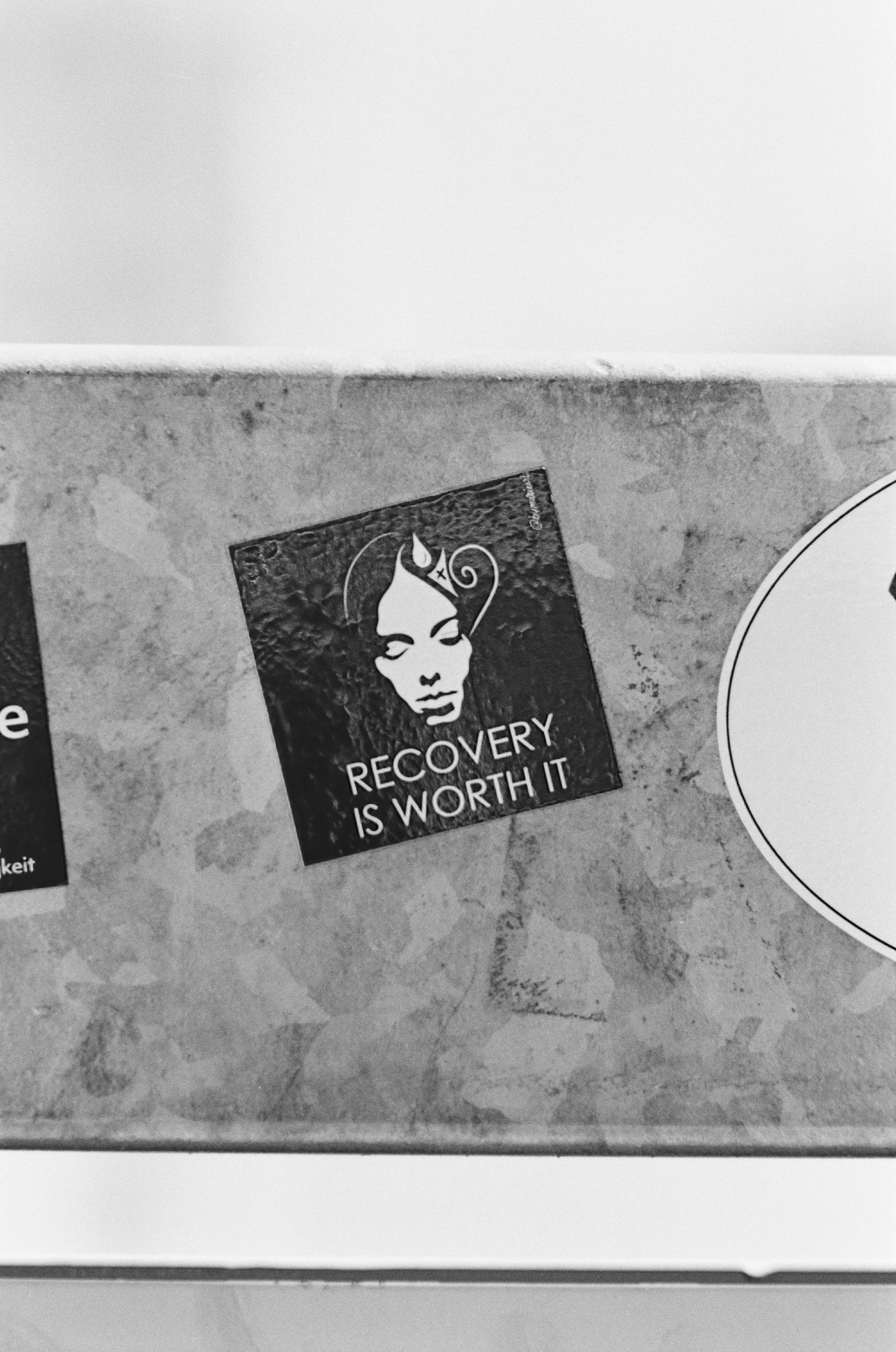 A black and white photo of a sticker that says recovery is worth it