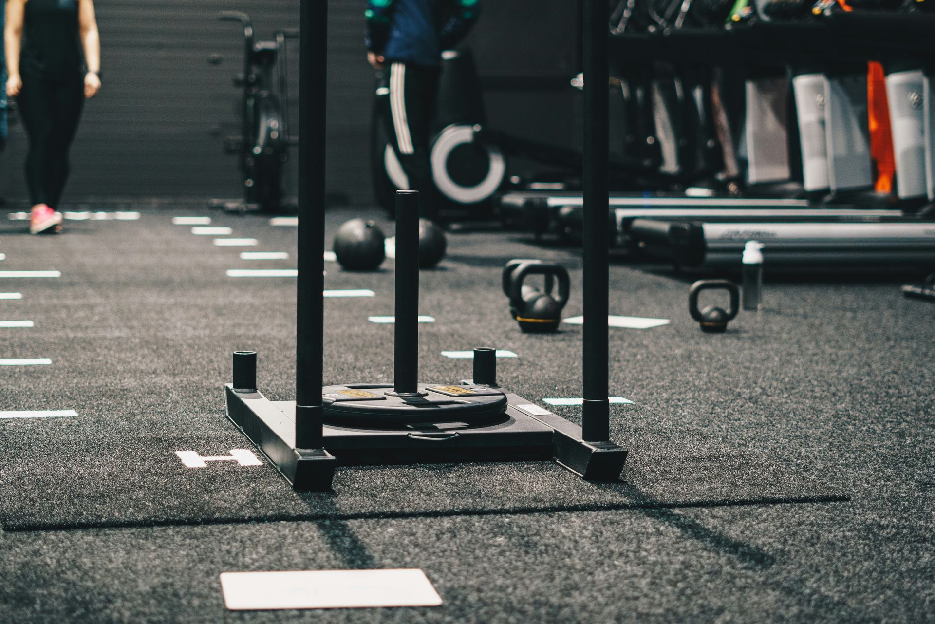 A person is pushing a sled in a gym.