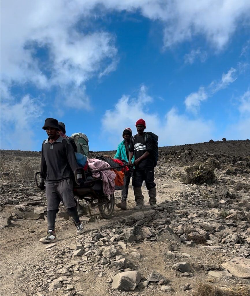 A group of people are walking down a dirt road.