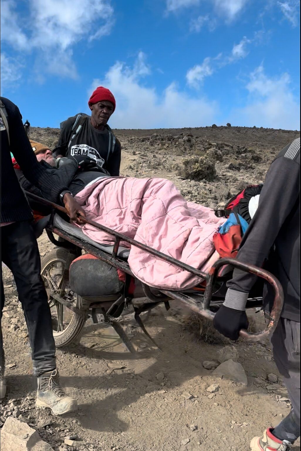 A person is laying on a stretcher in the desert.