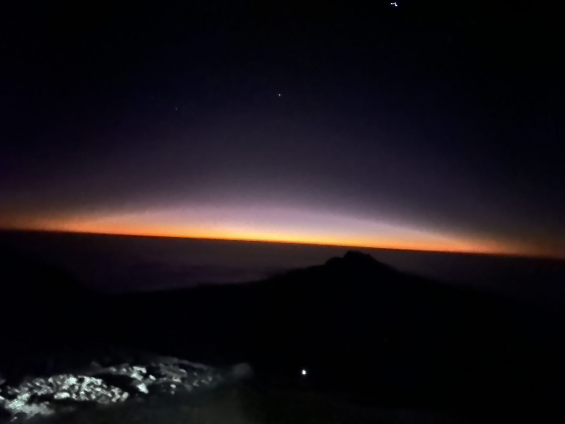 A dark night sky with a mountain in the distance