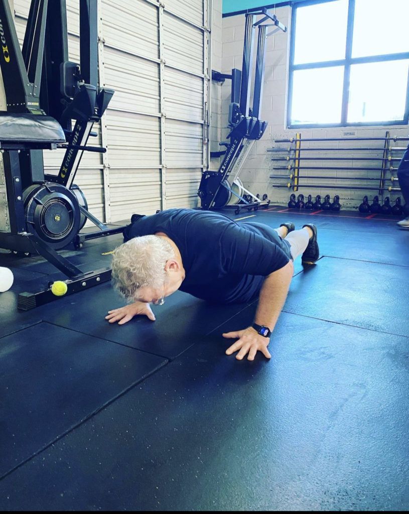 A man is doing push ups on the floor in a gym.