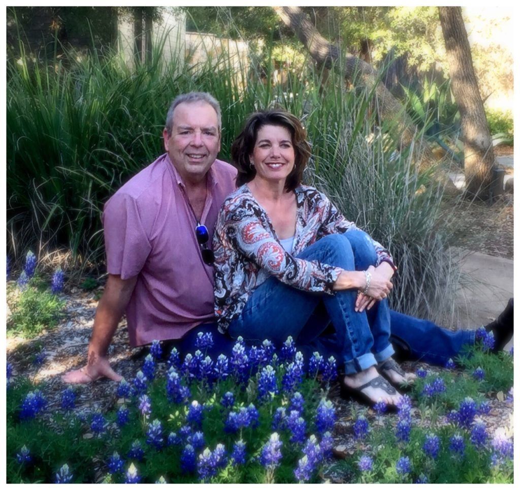 A man and woman are sitting in a field of blue flowers