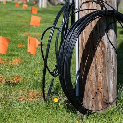a bunch of wires are sitting on top of a wooden pole in the grass .