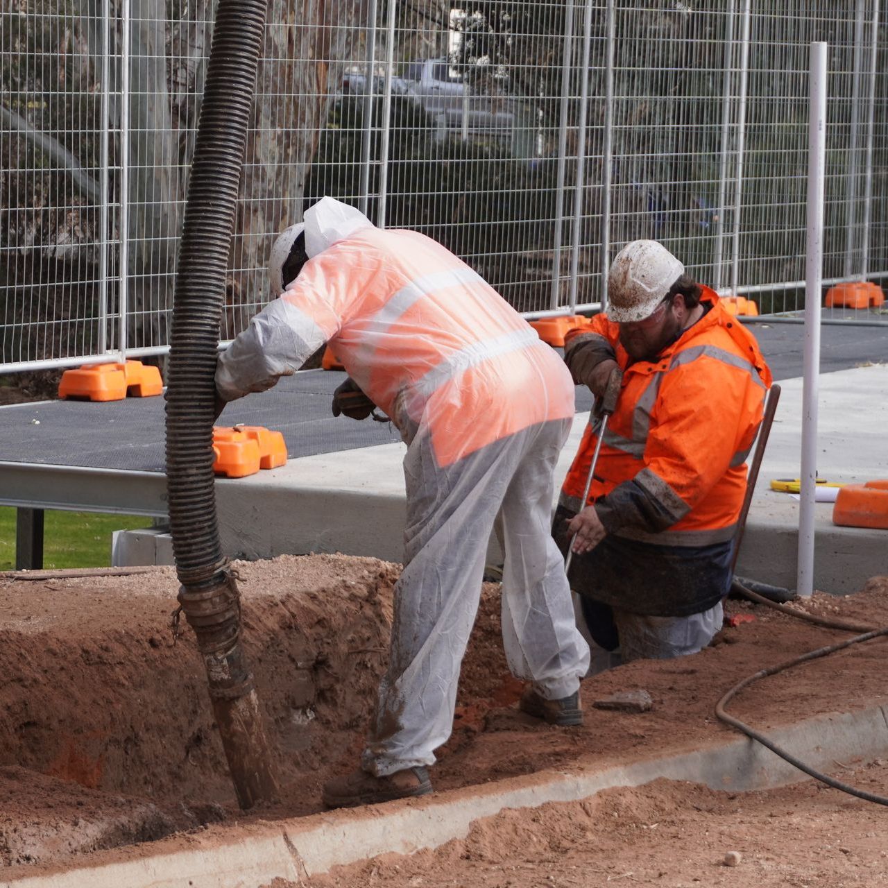 two construction workers are kneeling down in the dirt