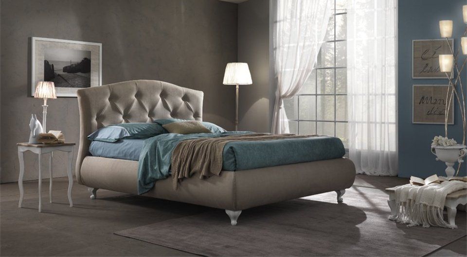 camera con arredi grigi e letto con testiera trapuntata