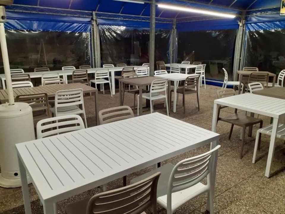 veranda esterna di un locale con sedie e tavoli beige e bianchi