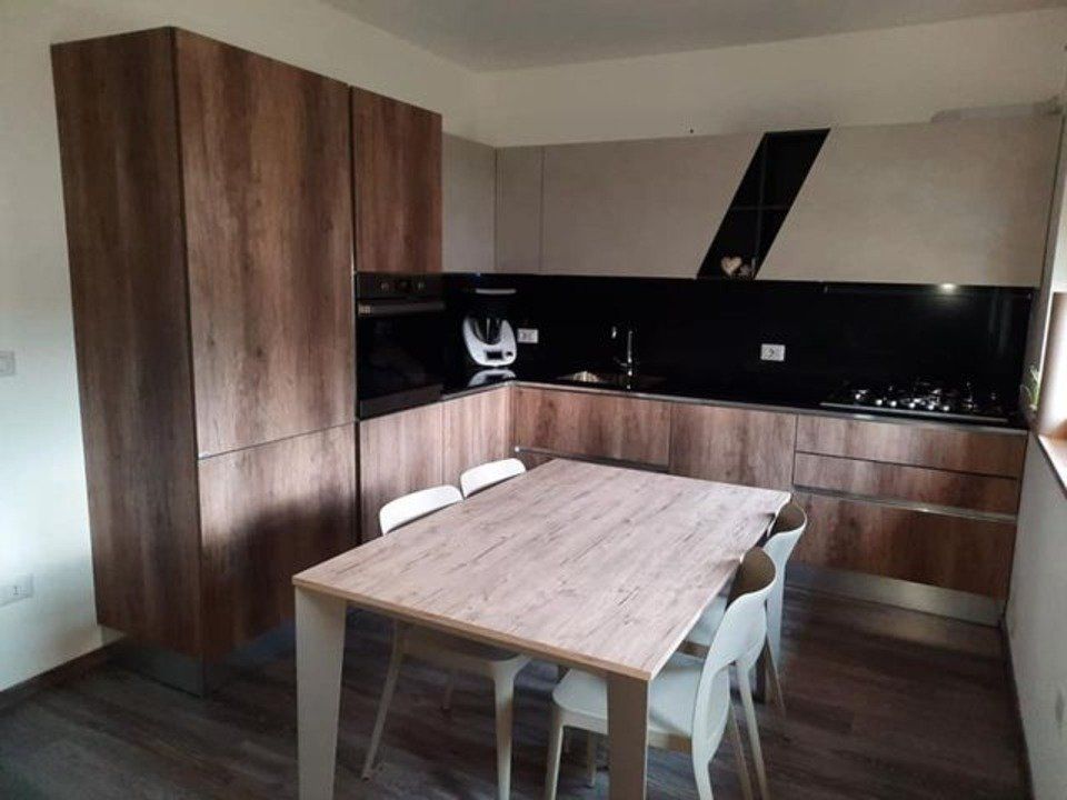 cucina con tavolo e moduli in legno e sedie bianche