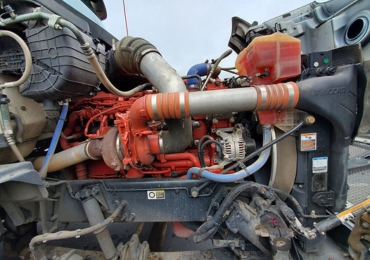Truck engine, primarily red, with various tubes and components visible.