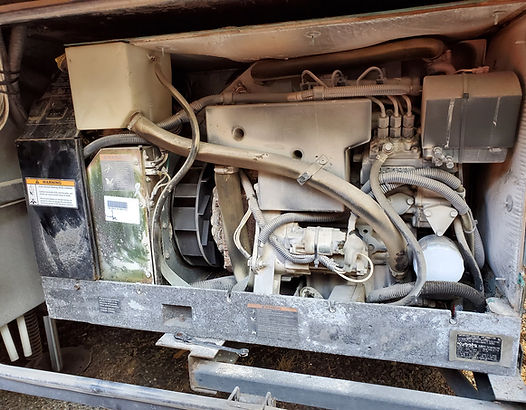 Dusty diesel engine within a metal enclosure, featuring various components and wiring.