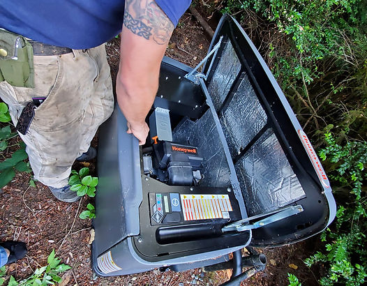 Person opens the lid of a black generator outdoors.