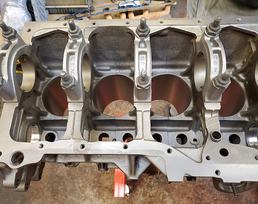 Engine block with exposed cylinders, showing main bearing caps and bolt holes.