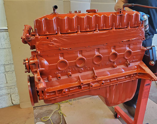 Red painted engine on a red engine stand; being spray painted.