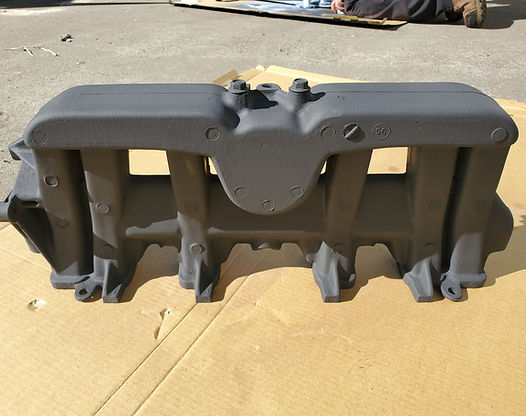 Gray intake manifold sitting on cardboard.