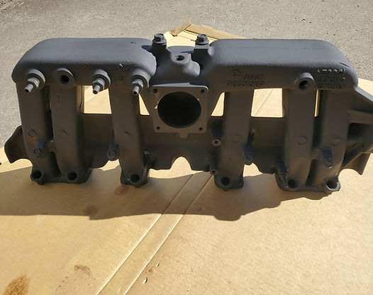 Gray intake manifold on cardboard.