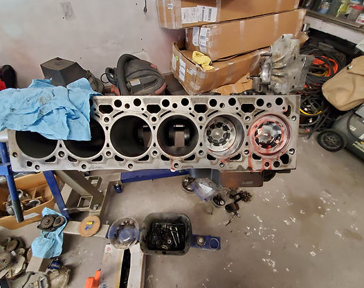 Engine block with cylinders, partially disassembled, on a stand in a workshop.