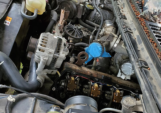 Engine compartment with exposed engine parts, including an alternator and valve covers.