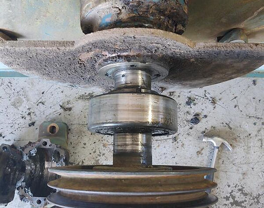 A close-up view of an old machine's pulley and shaft, covered in dust and grime.